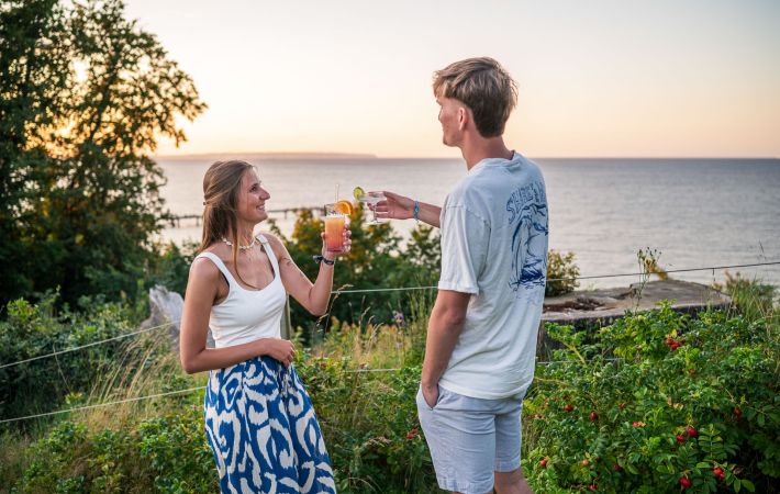 Gäste stoßen in der Gartenbar The Edge des Inselhotels Rügen mit Cocktails vor dem Meerblick an